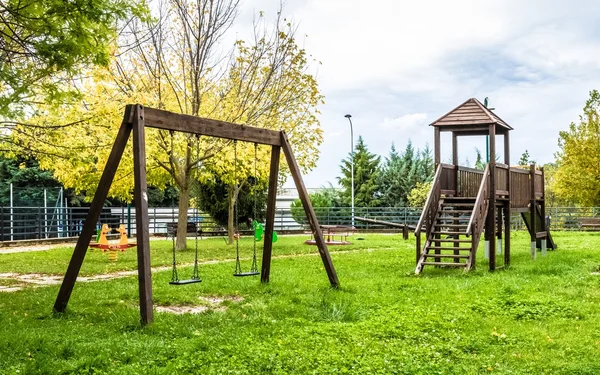 Altalene vuote al parco giochi per bambini vicino ai bambini scale scivoli attrezzature — Foto Stock