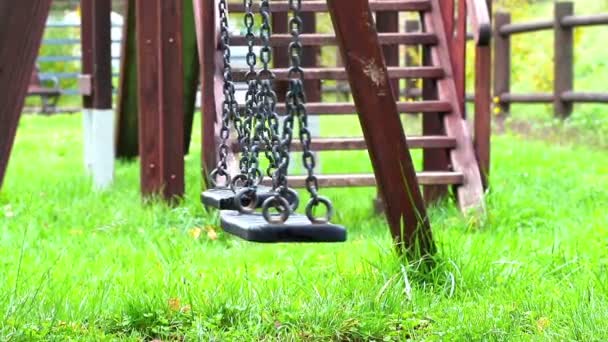 Порожні гойдалки, що ширяють на дитячому майданчику, переміщені з вітру — стокове відео