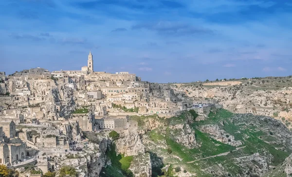 Panoramic view of typical stones (Sassi di Matera) and church near gravina of Matera UNESCO European Capital of Culture 2019 under blue sky — Stock Photo, Image