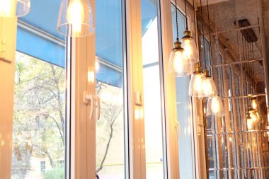 retro light bulbs on a red wire hang along a wooden window. lamps hanging from the ceiling along the window. warm glow comfort