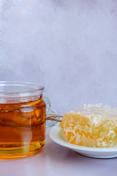 Vaso di vetro pieno di miele, piatto a nido d'ape su fondo marrone chiaro — Foto Stock