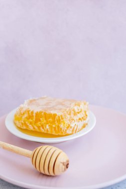 Tahta masanın üzerinde bal peteği ve kareli masa örtüsü açık kahverengi arka planda.