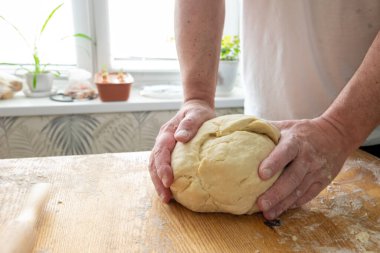 Erkeklerin elleri hamuru buruşturur. Mantı için hamur hazırlığı. Hamur ve hamur işlerinin adım adım tarifi.