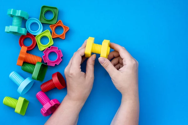 Ręce zbierają konstruktora edukacyjnego dla dzieci, nakrętek i śrub w postaci kształtów geometrycznych Obrazek Stockowy