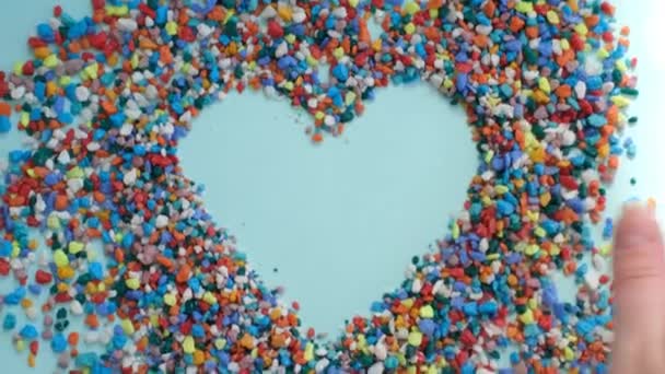Video hjärta bland små färgade stenar. Alla hjärtans dag tema. blå bakgrund. — Stockvideo