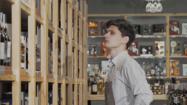 Fiatal férfi borász vásárol üvegeket a boltja polcain. — Stock videók