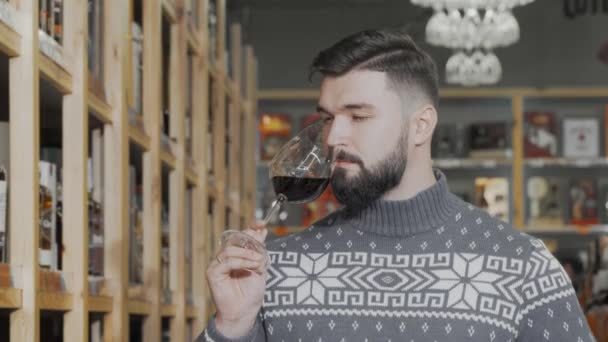 सुंदर आदमी शराब सुपरमार्केट में लाल शराब चख रहा है — स्टॉक वीडियो