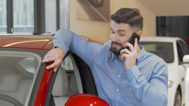 Hombre barbudo hablando por teléfono en el concesionario de automóviles — Vídeos de Stock
