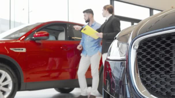 Prodejce a muž zákazník zkoumá automobil v autosalonu — Stock video