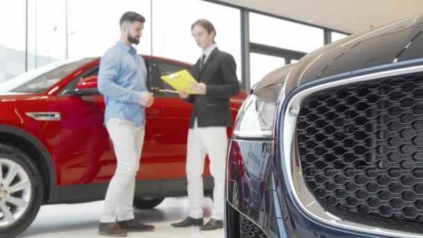 Male customer and salesman shaking hands at car dealership — Stock Video