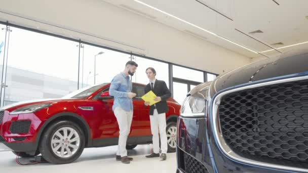 Skäggig man undersöker ny bil till försäljning hos återförsäljaren — Stockvideo