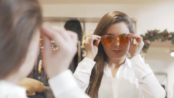 Belle jeune femme essayant de nouvelles lunettes de soleil au magasin de mode — Video