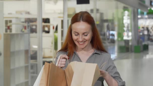 Mulher encantadora olhando em seu saco de compras no shopping — Vídeo de Stock