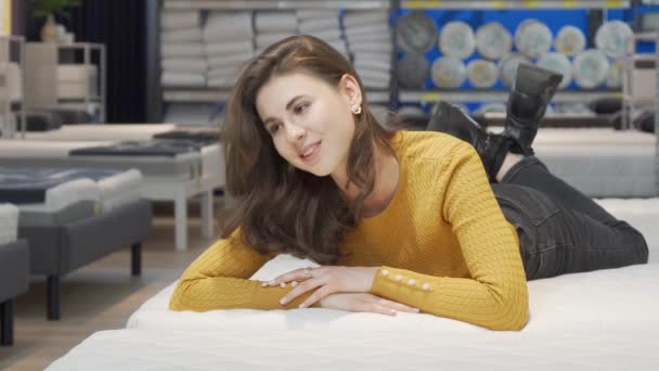 Härlig kvinna försöker ortopediska madrass på inredning butik — Stockvideo