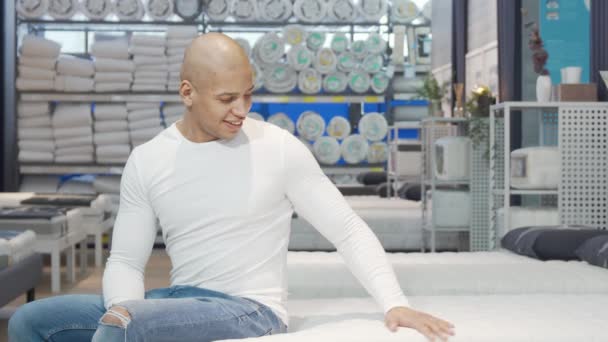 Vonzó férfi próbál új ágy a bútorboltban — Stock videók