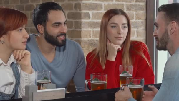 Groupe d'amis discutant autour d'un verre de bière au pub — Video