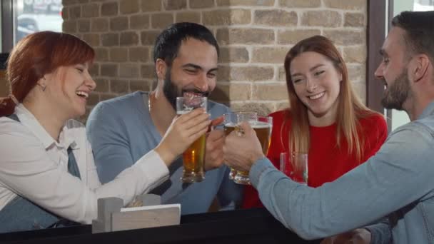 Alegre amigos tintineo vasos de cerveza en el pub — Vídeos de Stock