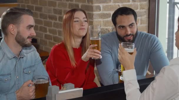 Счастливые друзья пьют в пабе бокалы для пива — стоковое видео
