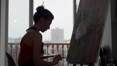 Stüdyosunda çalışan bir kadın ressamın silüeti.