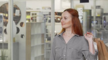 Çekici bir kadın alışveriş merkezindeki dükkanın vitrinine bakıyor.