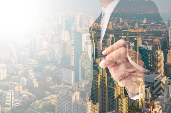 Businessman writing something on transparent board with city ref — Stock Photo, Image