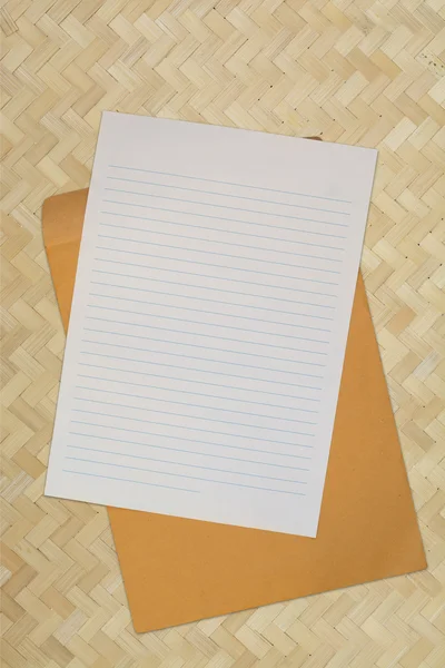 Papel em branco com envelope sobre fundo de tecelagem de bambu — Fotografia de Stock