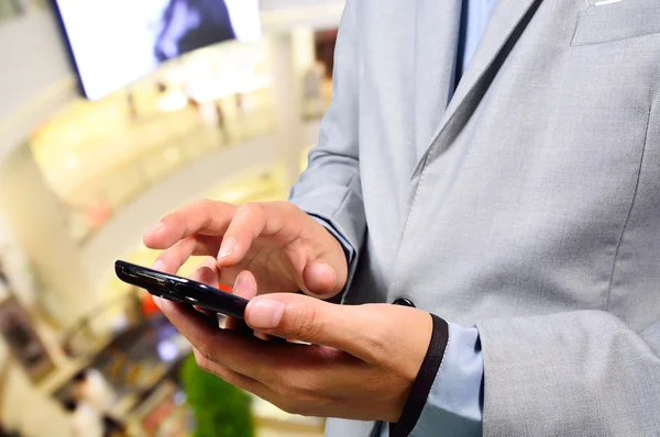 Obchodní muž používat mobilní telefon v nákupní centrum — Stock fotografie