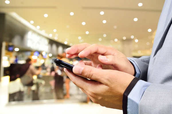 Pohledný mladý muž v nákupním středisku pomocí mobilního telefonu — Stock fotografie