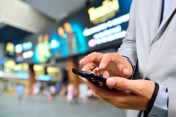 Pohledný mladý muž v nákupním středisku pomocí mobilního telefonu — Stock fotografie