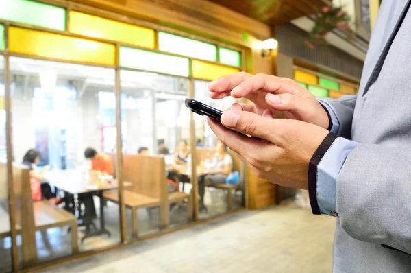 Liikemies käyttää mobiili älypuhelin Ravintola tai Food Cour — kuvapankkivalokuva