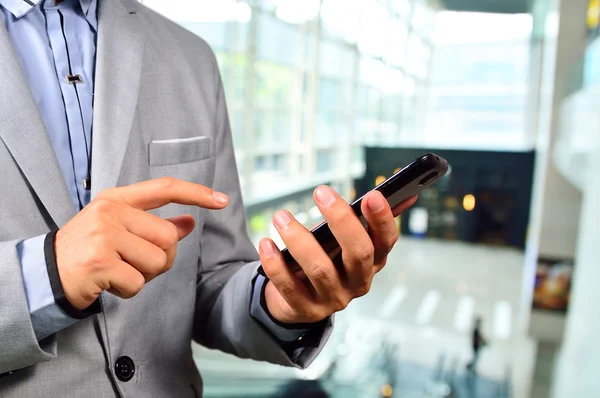 Hombre de negocios usando el teléfono celular móvil en el moderno edificio de oficinas —  Fotos de Stock