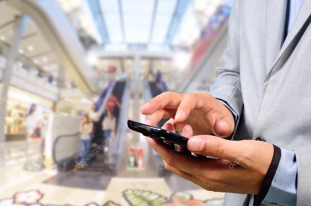 Handsome young man in shopping mall using mobile phone