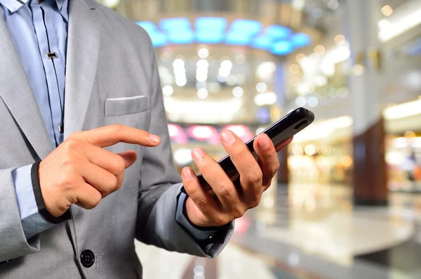 Beau jeune homme dans le centre commercial en utilisant une tablette mobile . — Photo