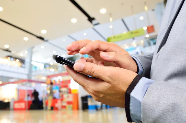 Obchodní muž pomocí mobilního telefonu v moderní nákupní centrum — Stock fotografie