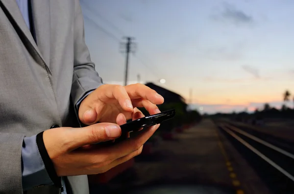 Hombre usando su teléfono móvil en la plataforma de ferrocarril vacía. Primer plano h —  Fotos de Stock