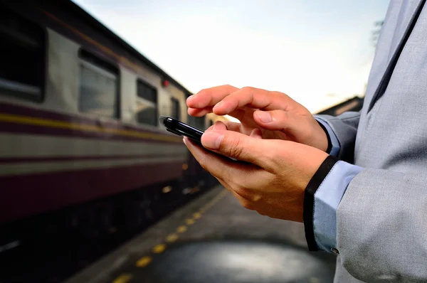 Muž, pomocí svého mobilního telefonu na prázdné nástupiště. Detail h — Stock fotografie