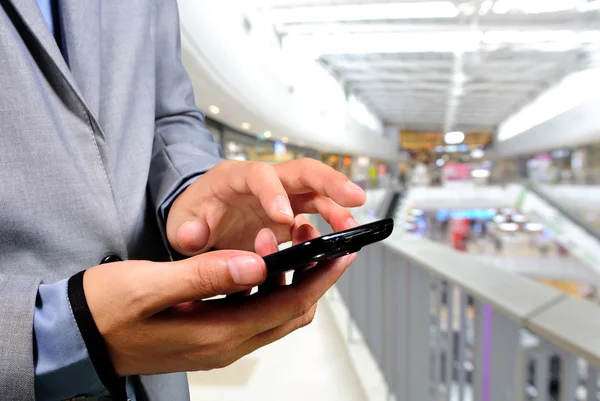 Pohledný mladý muž v nákupním středisku pomocí mobilního telefonu — Stock fotografie