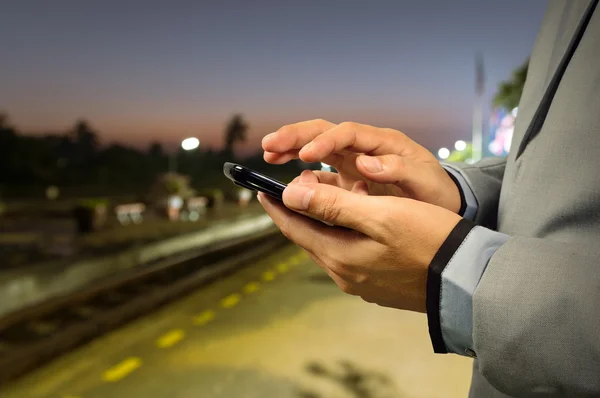 Obchodní muž použít mobilní telefon v železniční stanici — Stock fotografie