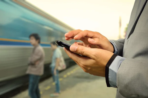Obchodní muž použít mobilní telefon v železniční stanici — Stock fotografie
