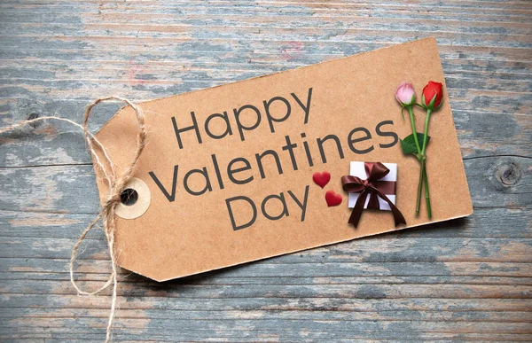 2つのバラとラップギフトボックスとラベルに手書きの幸せなバレンタインデー — ストック写真