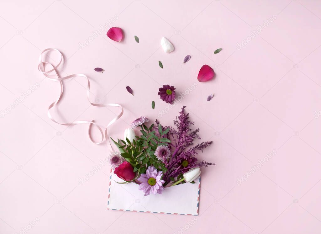 Assorted flowers falling out of an envelope with gift ribbon