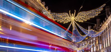 Regent Caddesi 'nin panoramik manzarası Noel ışıkları ve bir Londra otobüsünün ışık yolları..