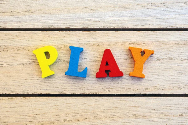 Play 这个词是用五颜六色的木制字母拼写出来的 — 图库照片