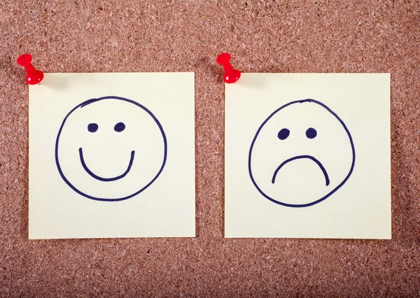 Caras felices y tristes sujetadas a un tablón de anuncios — Foto de Stock