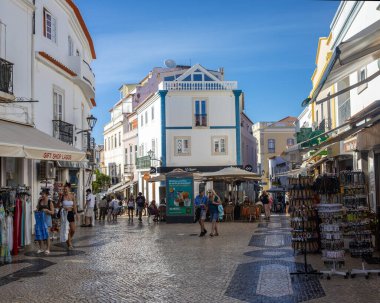 Lagos, Portekiz - 21 Eylül 2025: Portekiz 'in eski Lagos kentindeki Rua 25 de Abril' in güzel bir manzarası. Cadde restoranlar, butikler ve hediyelik eşya dükkanlarıyla dolu..