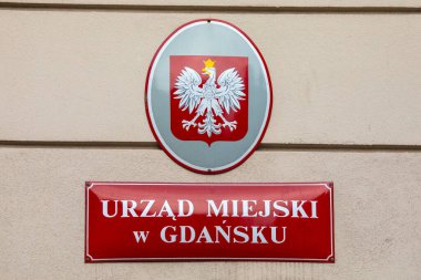 Polonya 'nın Gdansk kentindeki bir devlet dairesinin dış cephesinde bir tabela ve şehir arması var..