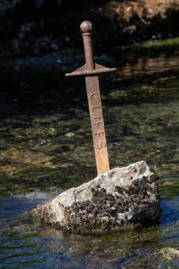 Somerset, İngiltere - 16 Mayıs 2025: İngiltere 'nin Somerset kentindeki Cheddar köyünden akan Çedar Yeo nehrindeki Taş heykeldeki Kılıcın görüntüsü.