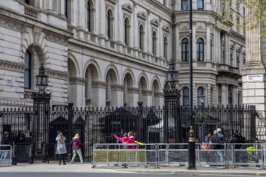 Londra, İngiltere - 8 Nisan 2024: Londra, İngiltere 'deki Downing Street girişindeki kapılardan ve güvenlikten bakan turistler. Hükümet, İngiltere Başbakanı 'nın ikametgahıdır..