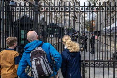 Londra, İngiltere - 8 Nisan 2024: Londra, İngiltere 'deki Downing Street girişindeki kapılardan ve güvenlikten bakan turistler. Hükümet, İngiltere Başbakanı 'nın ikametgahıdır..