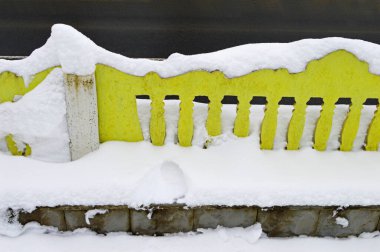 Taze karla kaplı sarı bir çitin parçası.